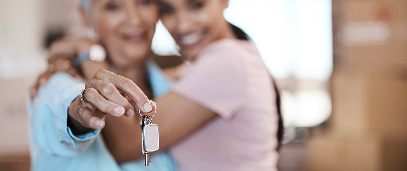 Two women holding up a house key.