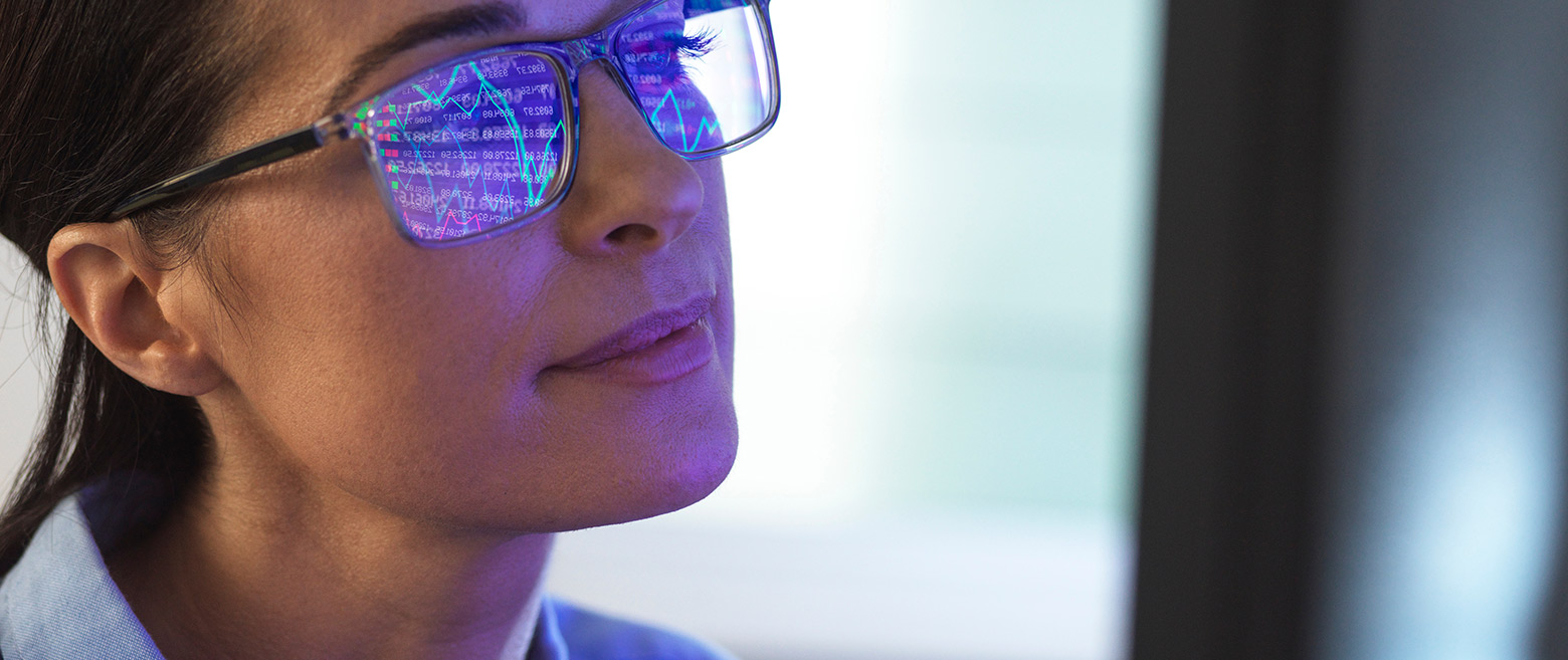Women wearing glasses looking at a digital screen of charts.