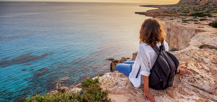 Woman sitting on cliff looking at ocean